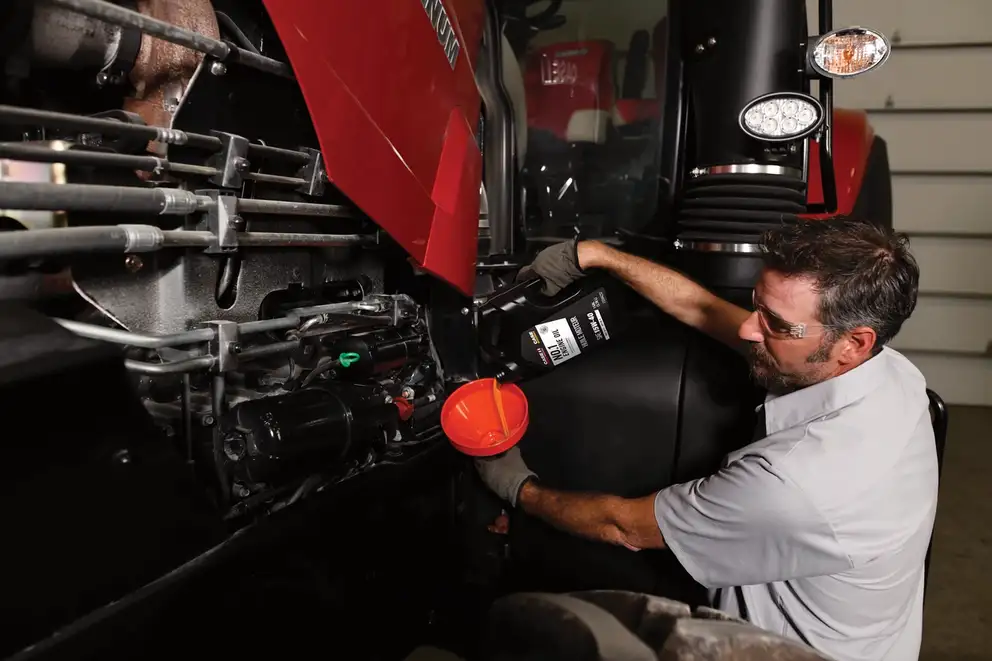 Case IH technician pouring oil into funnel