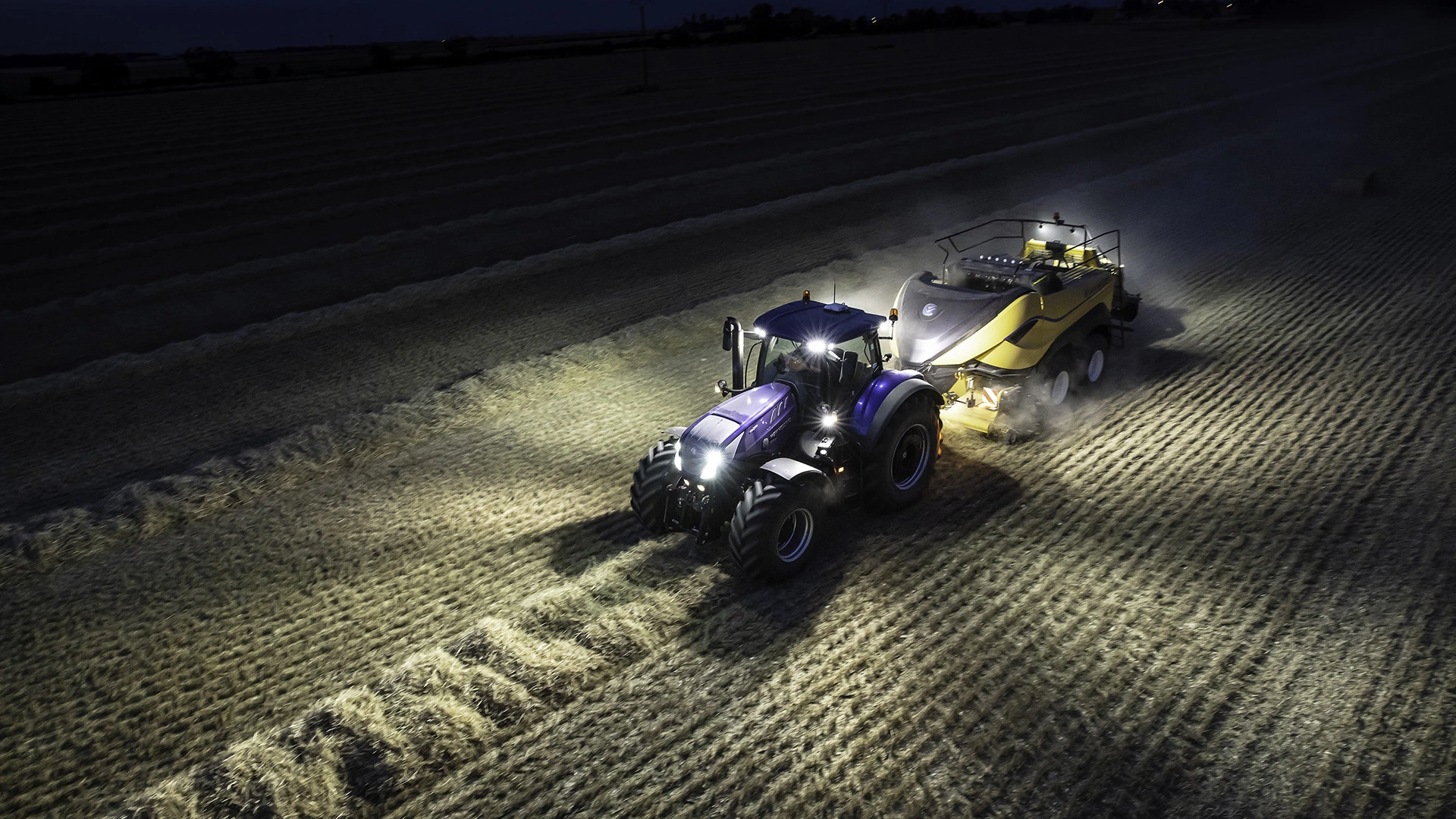 Tractor in action, operating a Bigbaler High Density on an agricultural field during the night