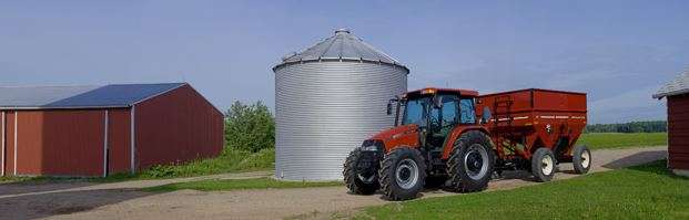 Case IH tractor with wagon in front of silo