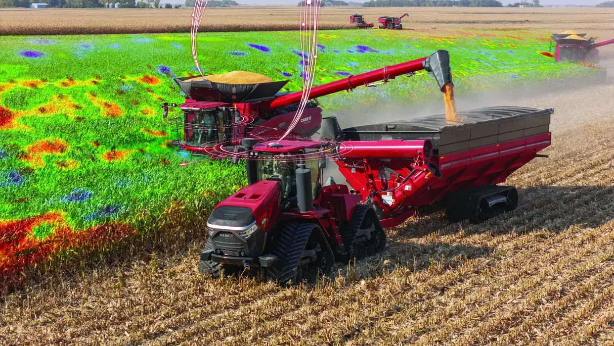 Case IH combine harvester on a field unloading grain, with a vibrant, multicolored heat map overlay indicating crop yield variations.