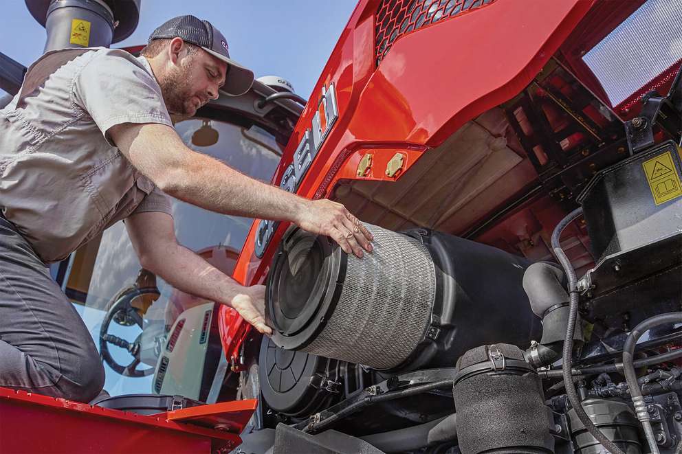 Man replacing filter on Case IH tractor machine
