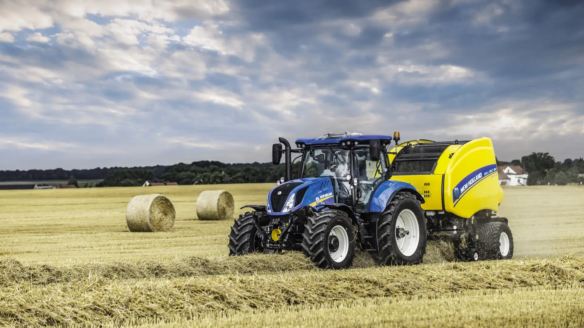 Tractor and Roll-Belt round baler combination actively bundling hay on the farmland
