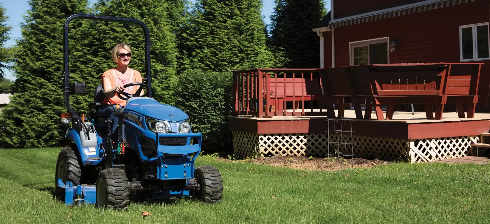Woman operates WORKMASTER 25S tractor with a belly mower
