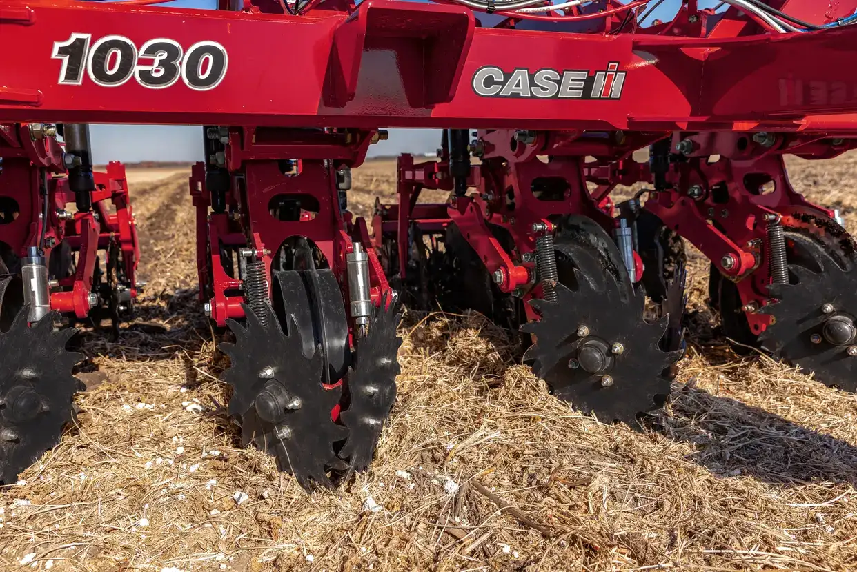 Close-up of the tillage components on a Case IH Nutri-Tiller 1000 series strip tillage tool as residue managers sweep away surface material on the ground.
