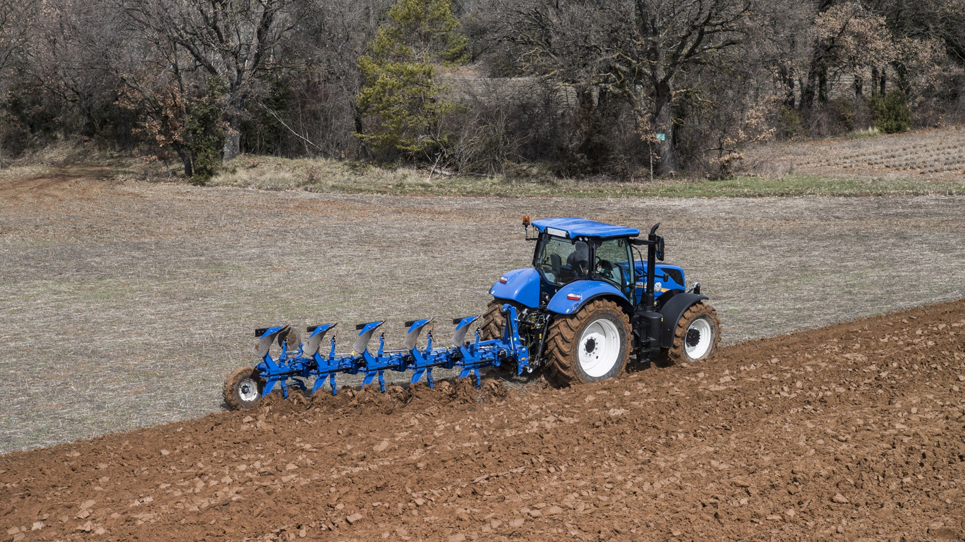Tractor with New Holland's 5 furrow fully-mounted variable width reversible plough