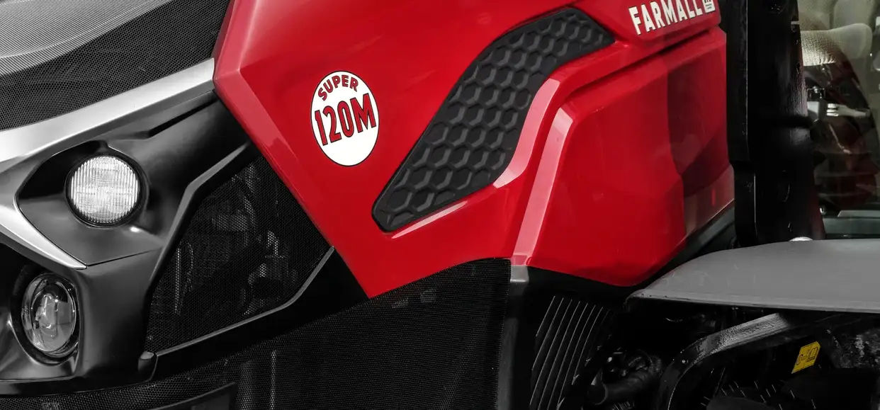 Close-up of the red Case IH Farmall tractor hood showing the Super 120M logo and front headlights.