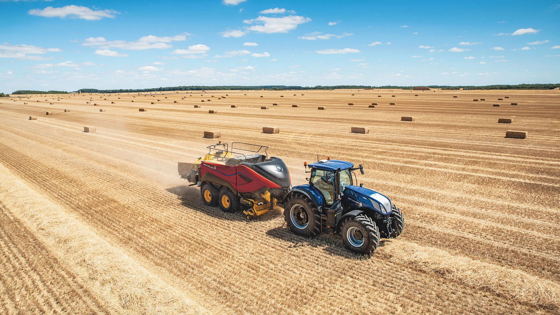 Tractor pulls a BigBaler High Density Large Square Balers while baling in the field