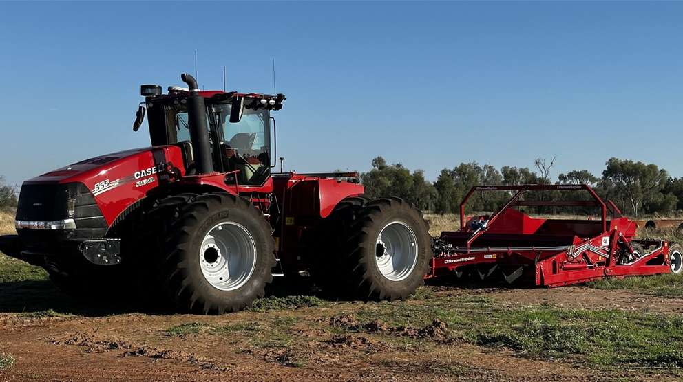 Red Case IH tractor with attachment sitting in field in the sun