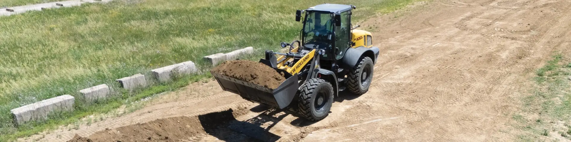 Compact wheel loader lifting a pile of dirt.