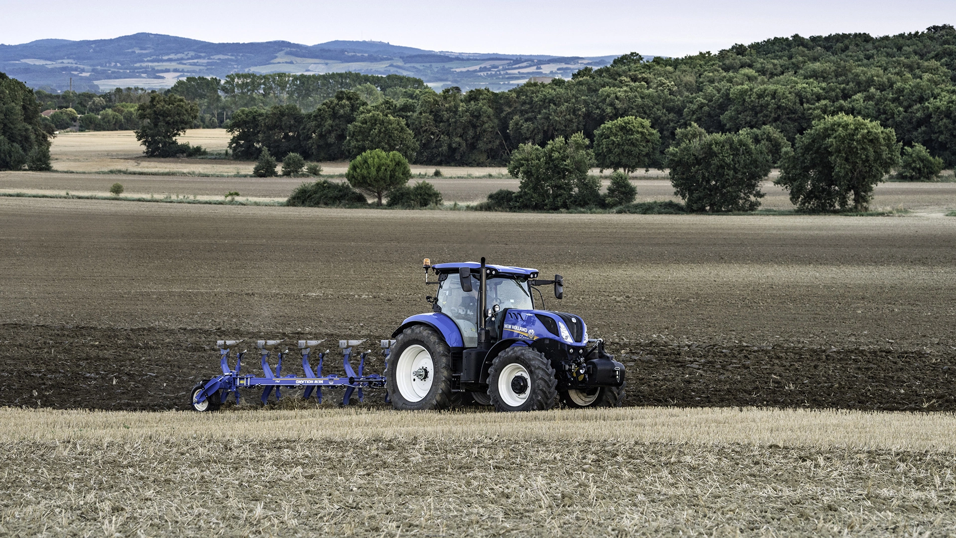New Holland tractor equipped with an agricultural plough in the field