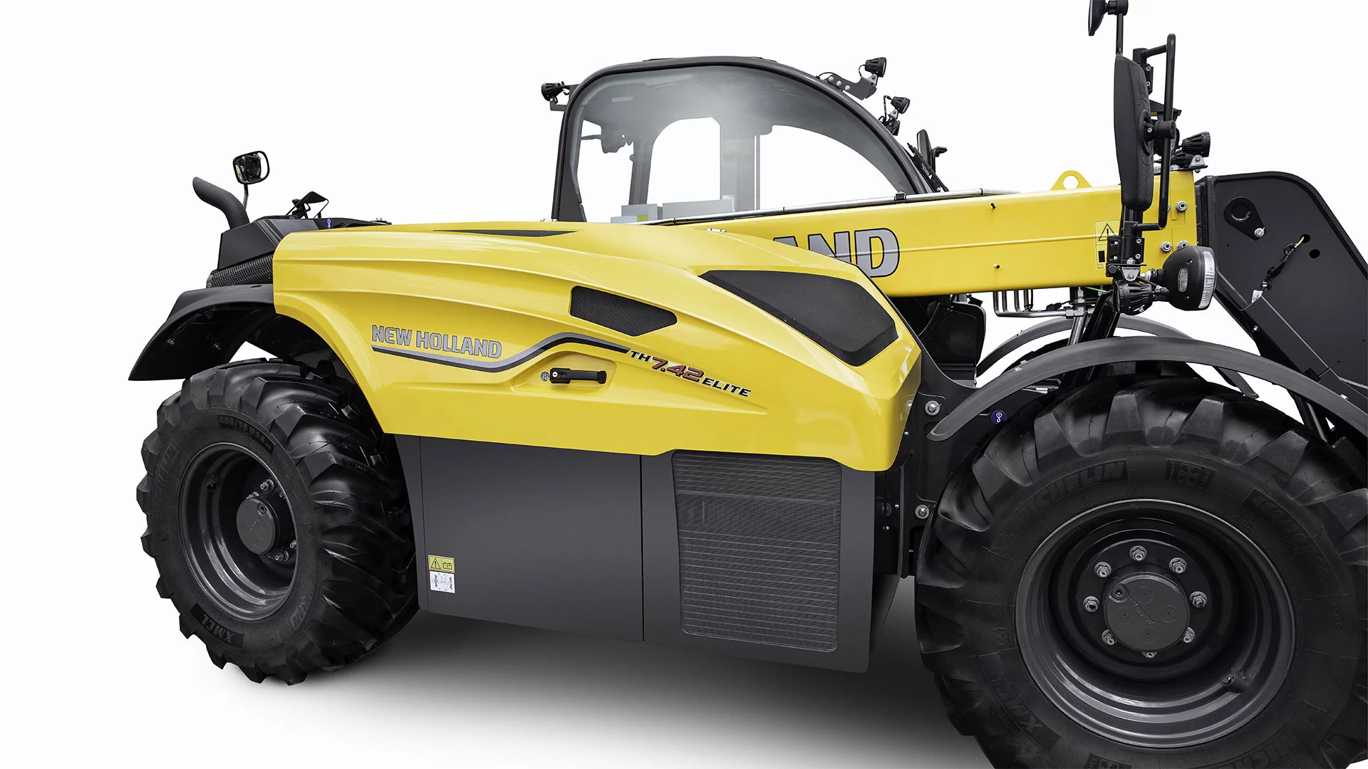 Close-up view of a New Holland TH 7.42 Elite telehandler, highlighting its yellow and black design, large tires, and detailed bodywork.