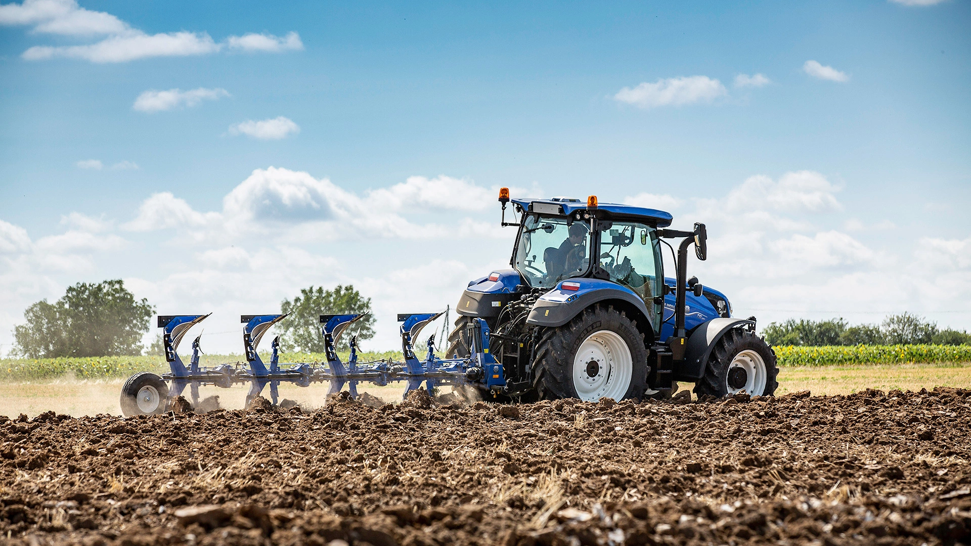 Farming tractor New Holland T5 Dynamic Command & Auto Command with a plough in action on agricultural land