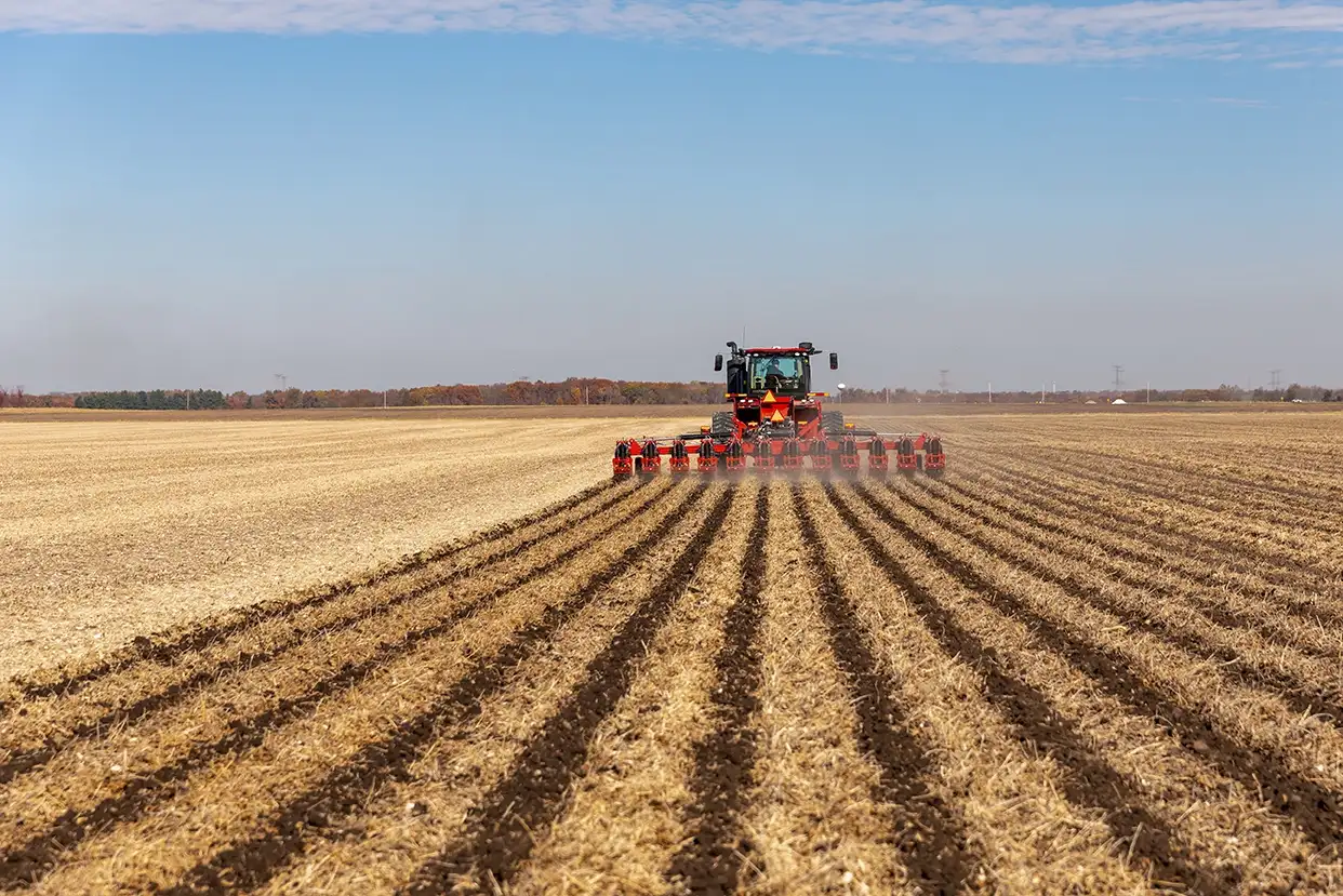 A Case IH tractor with a Nutri-Tiller 1000 series strip tillage tool passes through a harvested field, leaving even and well-formed berms.