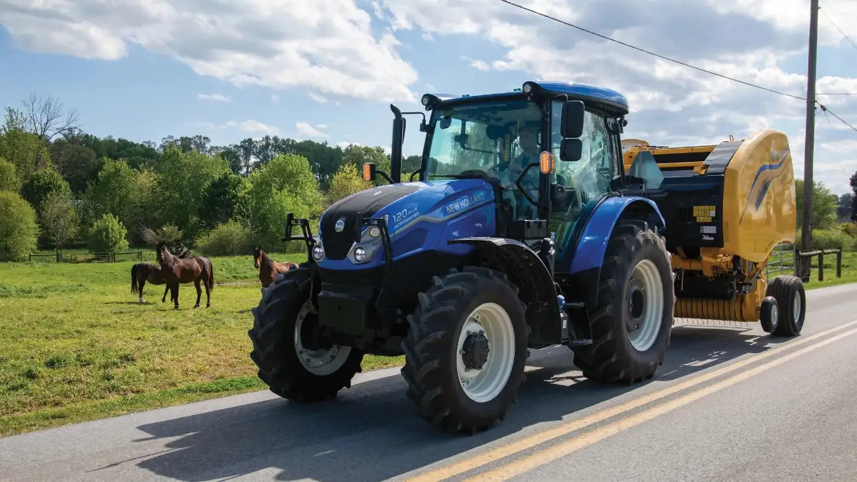 WorkMaster tractor pulling hay baler on the road.