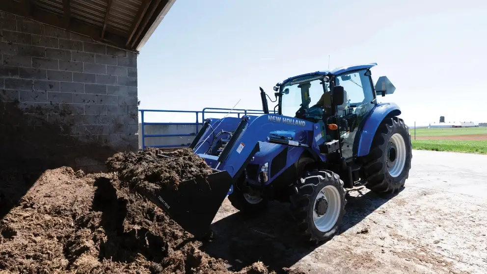 Blue tractor lifts dirt under a building.