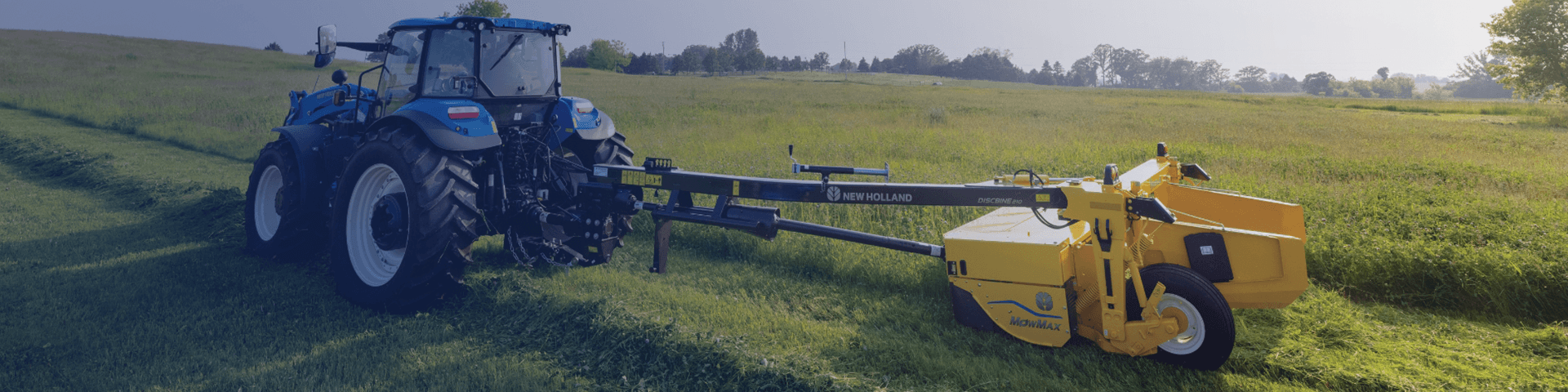 New Holland Discbine side-pull conditioner working in field with blue New Holland tractor