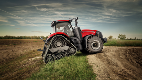 Red Case IH Magnum 405 tracked tractor at the edge of a ploughed field under a cloudy sky.