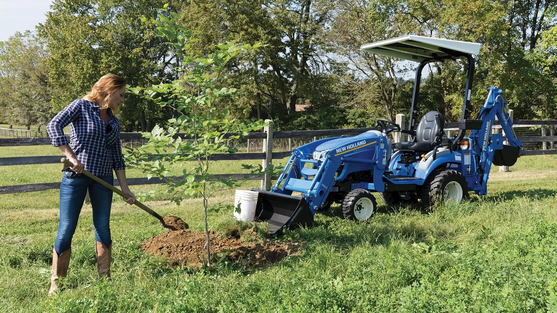 Woman shovels dirt next to a WORKMASTER 25S tractor