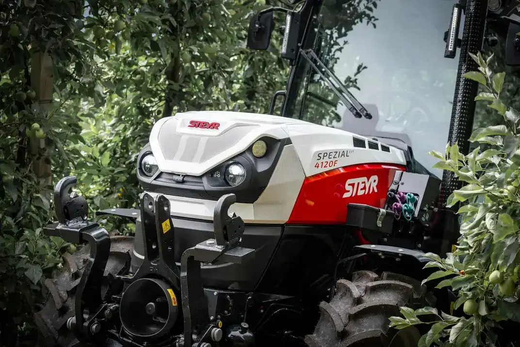 Nahaufnahme von Front und Motorhaube eines STEYR Spezial 4120F Obstbautraktors zwischen Apfelbäumen