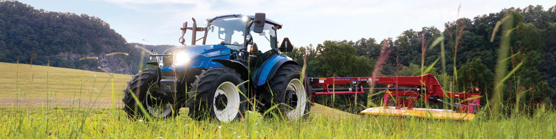 Tractor pulling disc mower in a field.