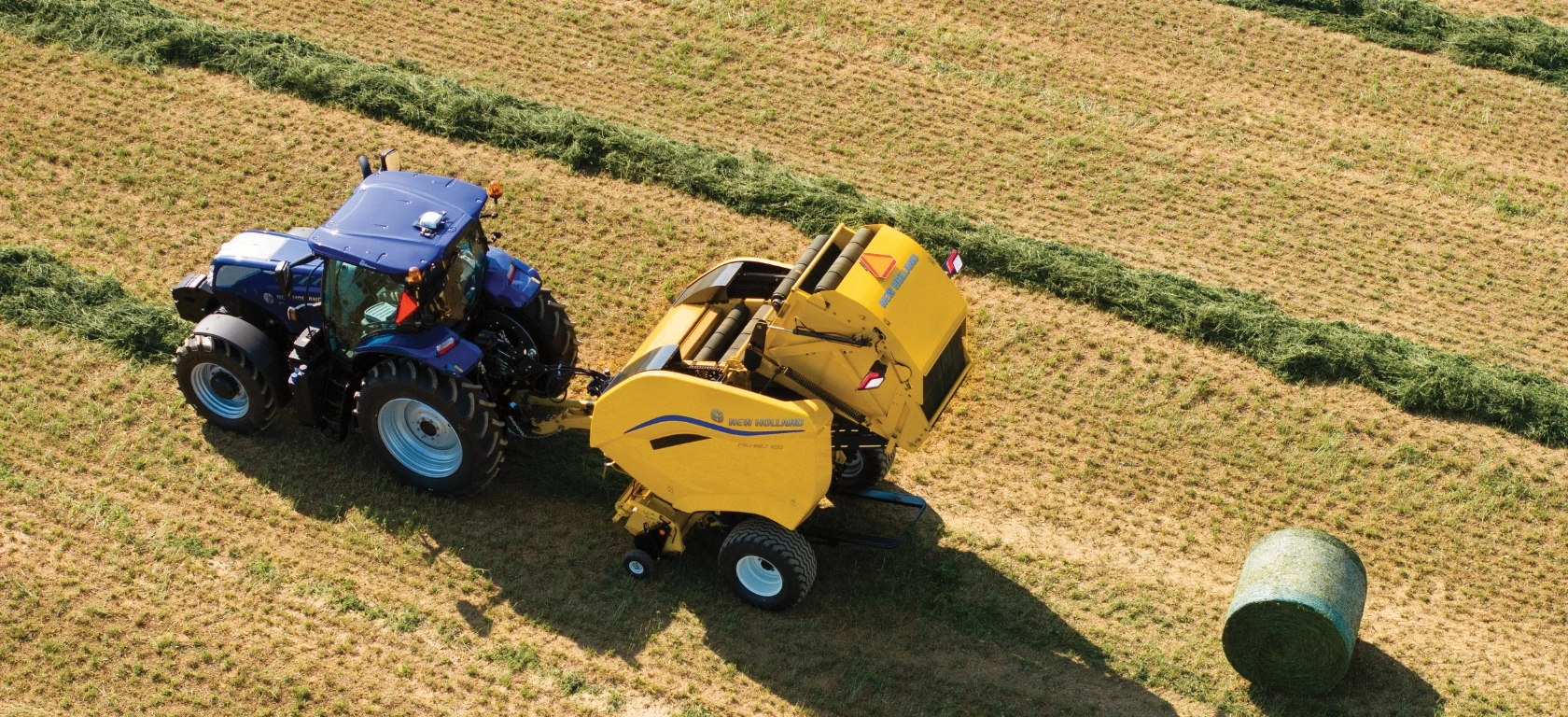 Tractor pulls a Pro-Belt™ Round Baler in the field