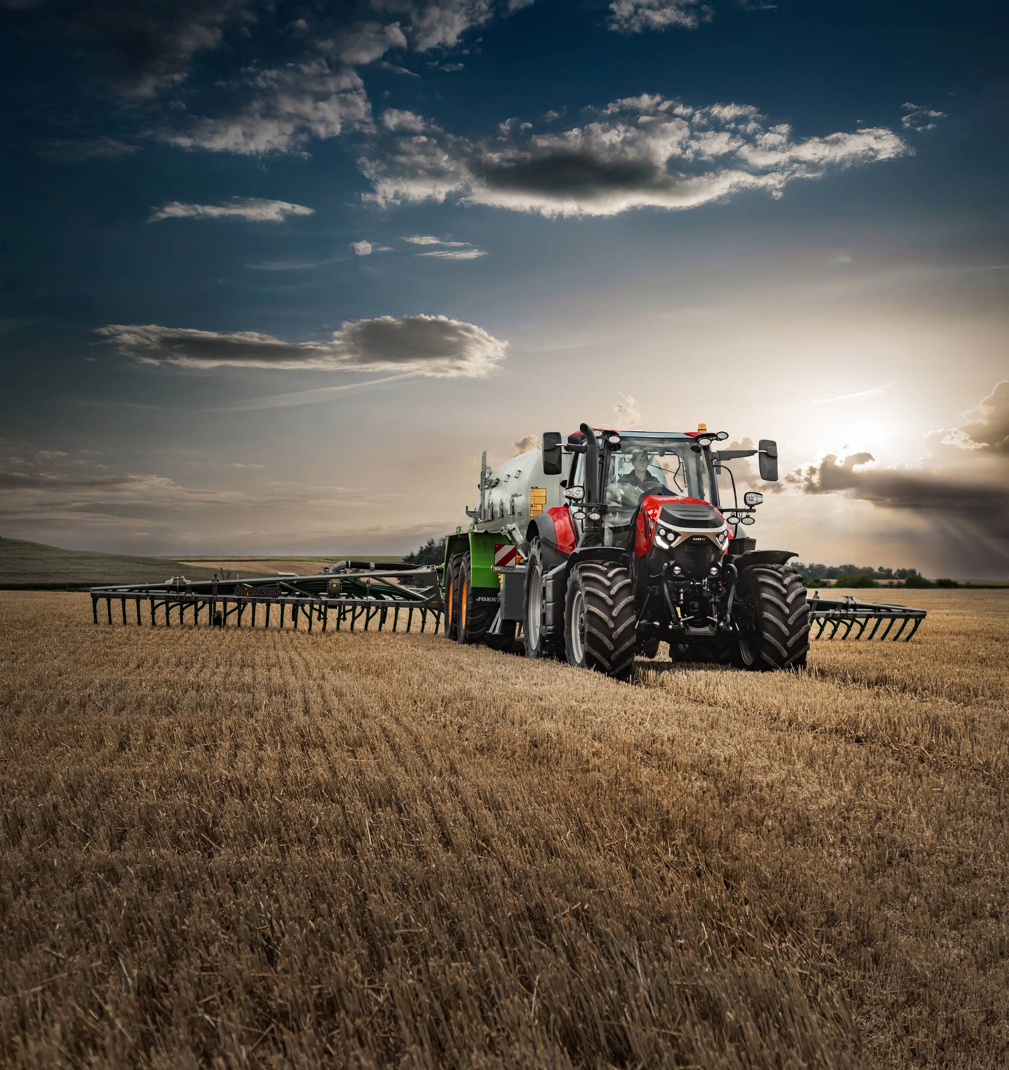 Case IH Puma 185 tractor pulling a green seeder through a golden field at sunset.