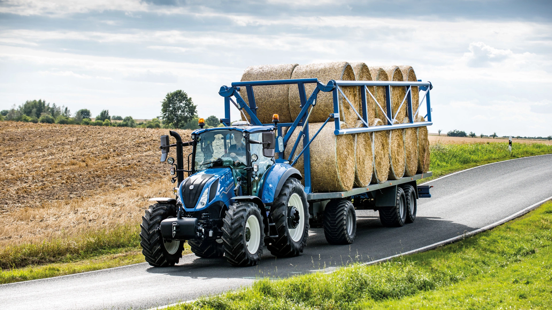 New Holland T5 Electro Command tractor in motion, transporting agricultural supplies