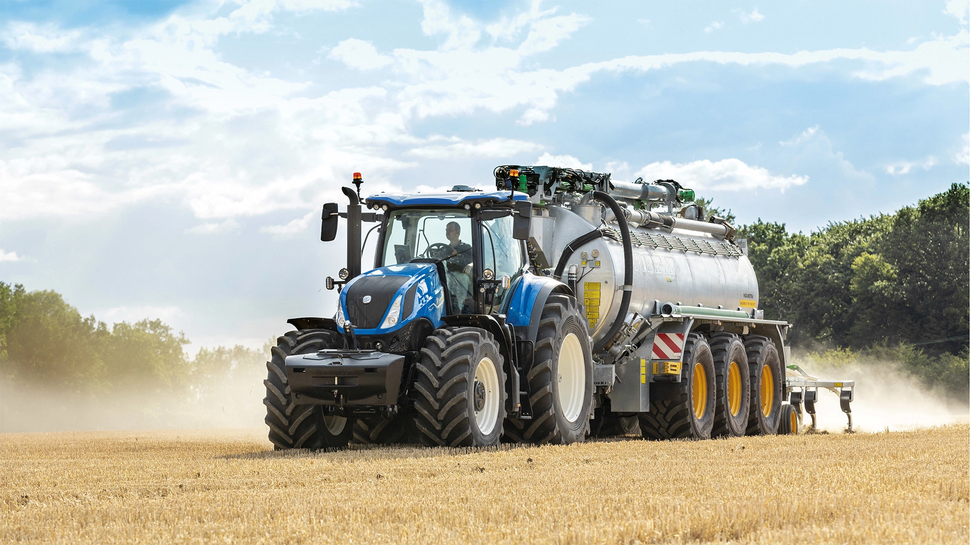 T7 Heavy Duty With PLM Intelligence tractor in motion, pulling a loaded trailer