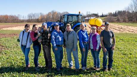 Family stands in front of a New Holland tractor