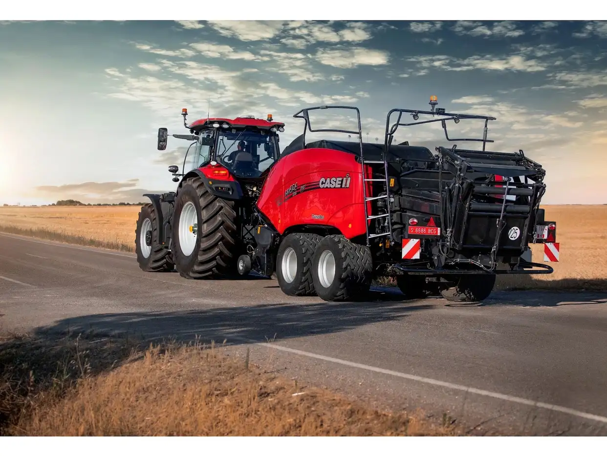 Case IH tractor towing a Case IH LB424 large square baler on a road at dusk