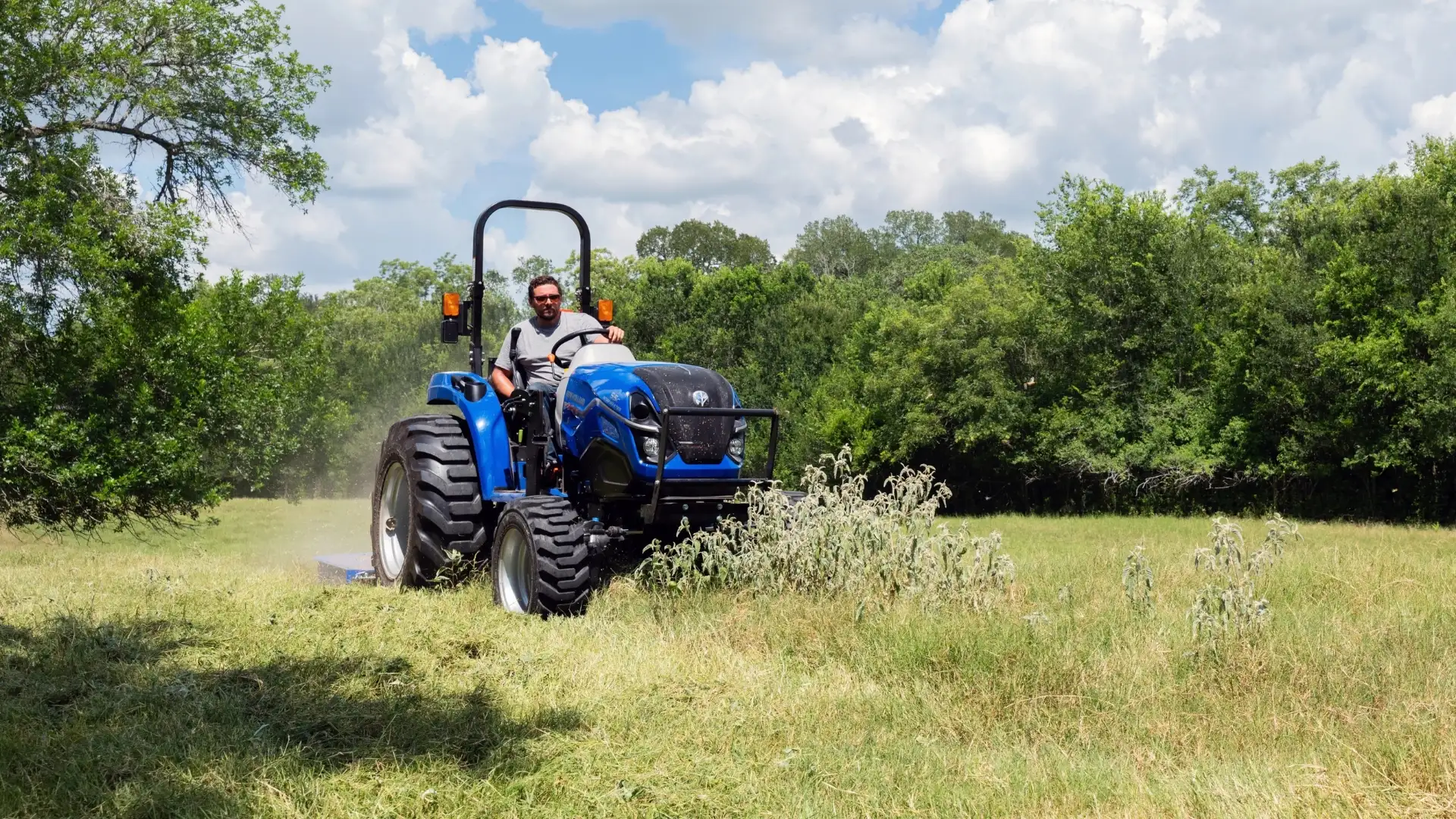 Blue tractor mowing in a field.