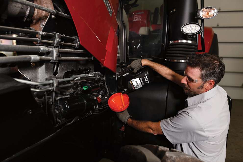 Case IH technician pouring oil into funnel