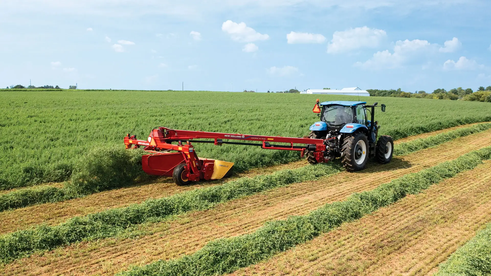 Tractor pulls a Discbine® PLUS Center-Pivot Disc Mower-Conditioner in the field