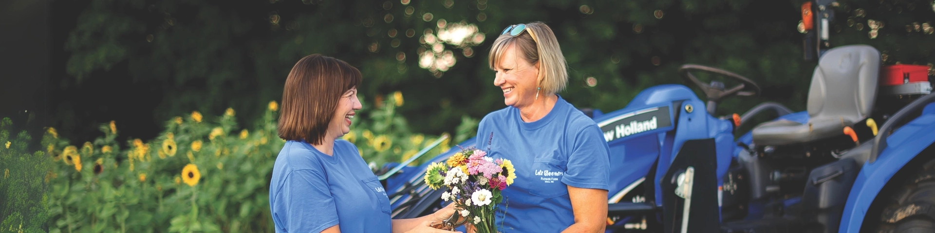 Women hold flowers in front of a New Holland tractor