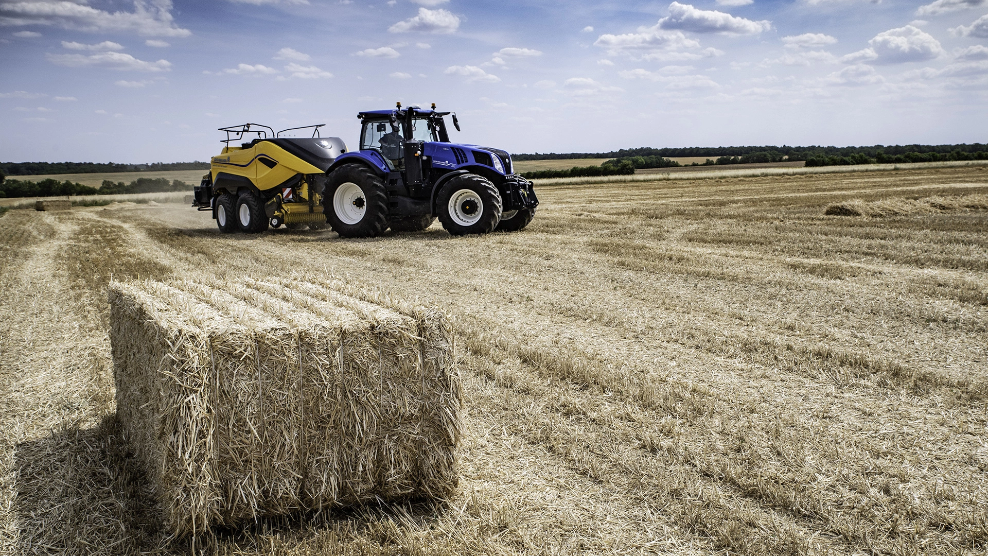 Farm tractor and Bigbaler High Density working in tandem, baling hay in the field