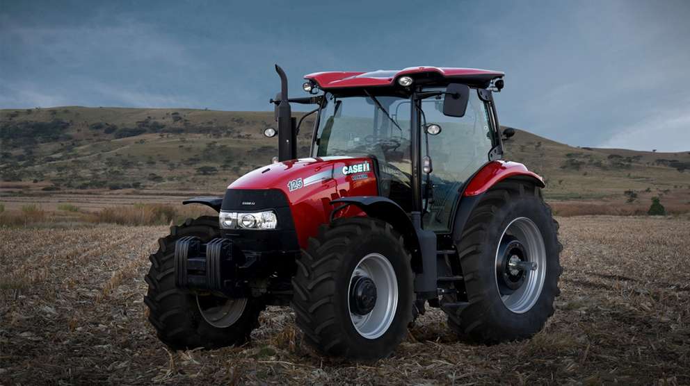 Red Case IH Maxxum tractor sitting in field with hill background