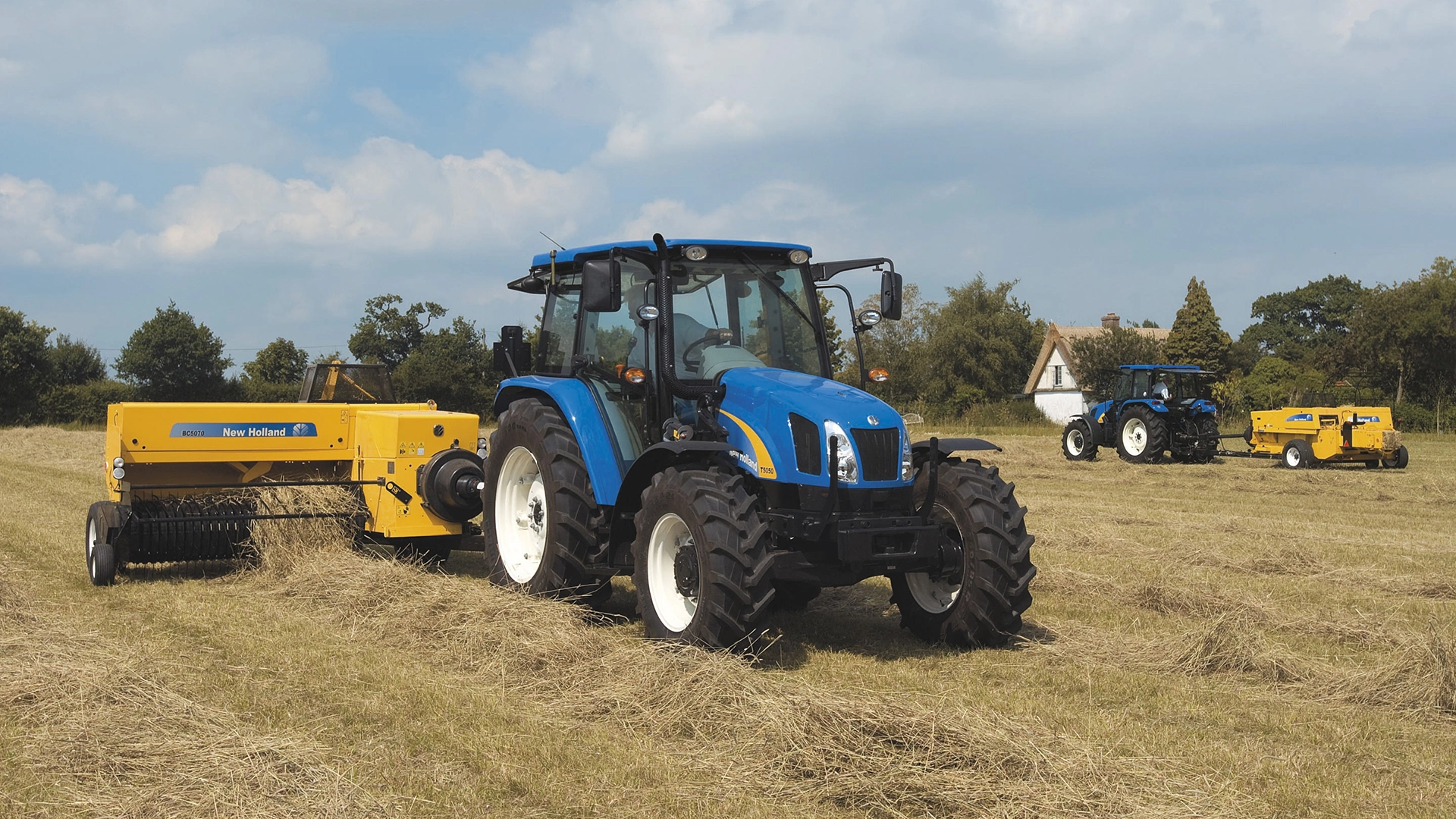 Pair of New Holland tractors operating BC5000 balers in a rural field.
