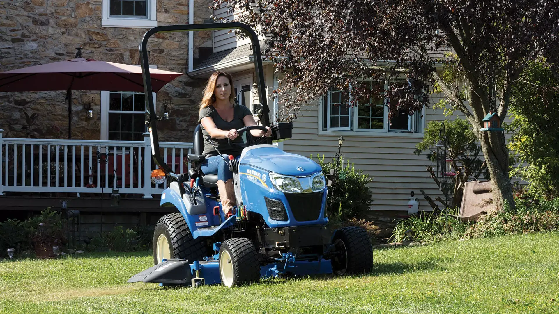 Woman operates WORKMASTER 25S tractor with a belly mower