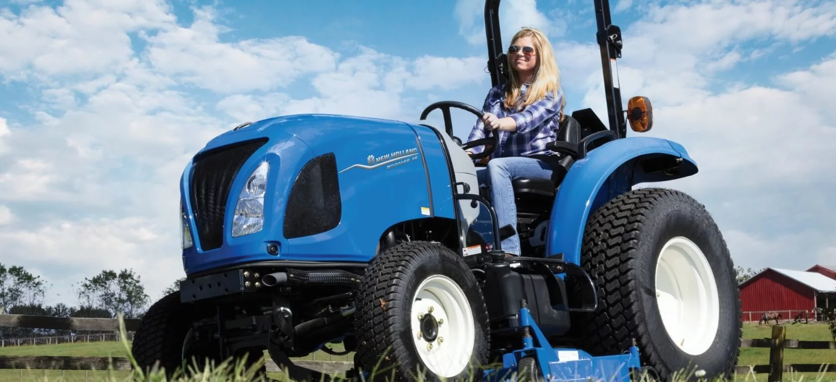 Woman operates Boomer tractor with a mowing attachment