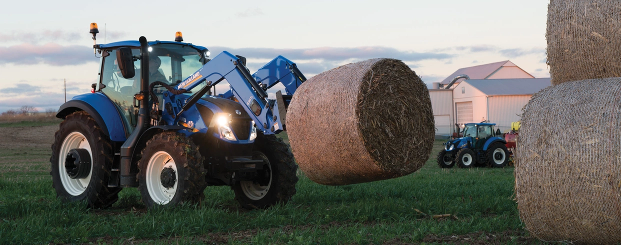 T5 Series tractor lifts a bale