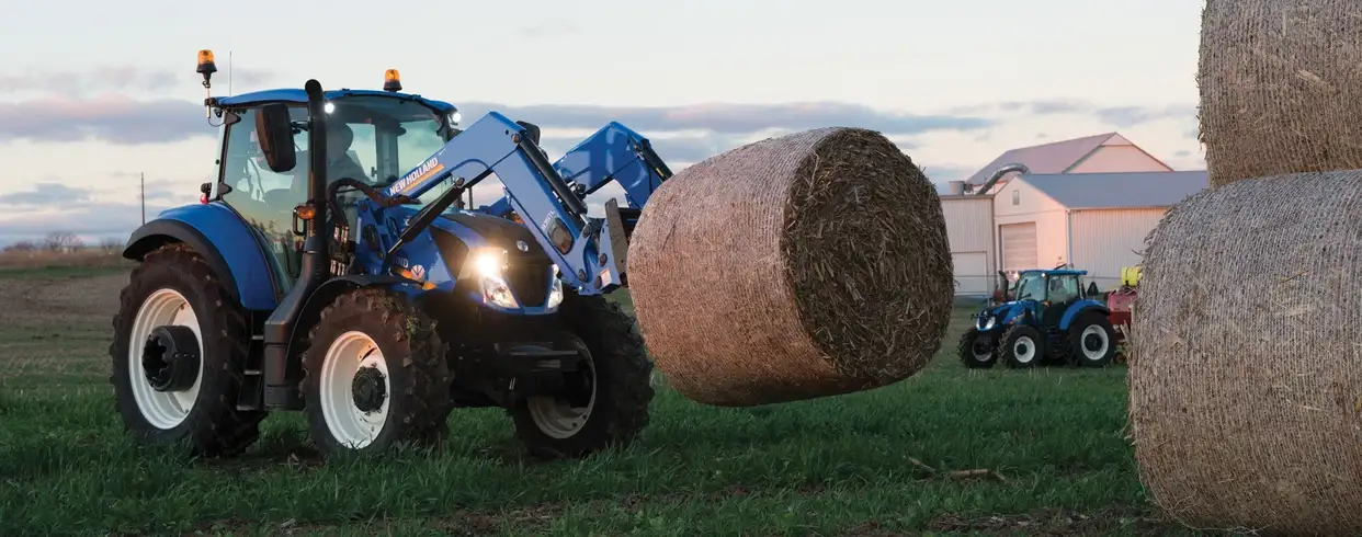 T5 Series tractor lifts a bale