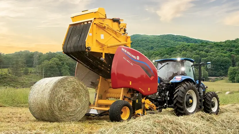 New Holland tractor pulls a baler while making hay.