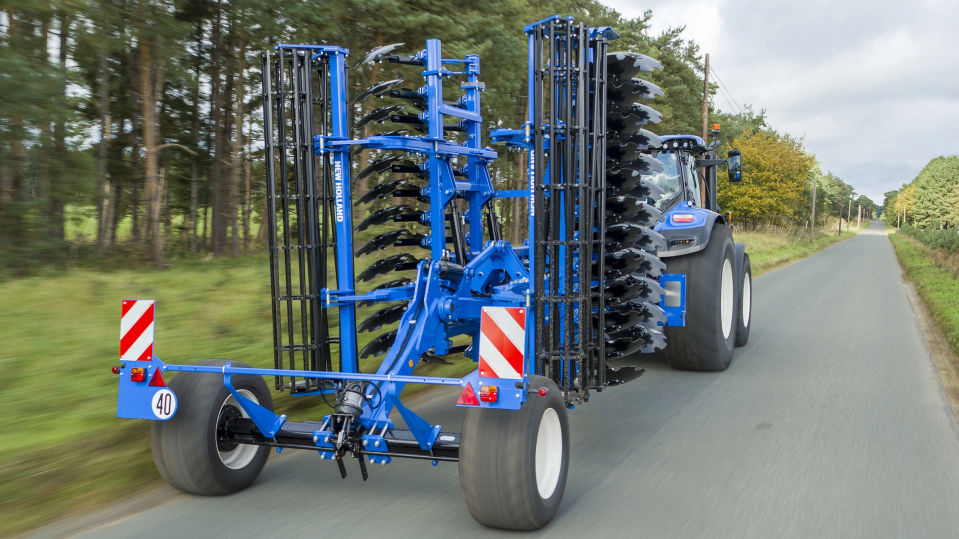 New Holland tractor transporting SDM & SDH Disc Cultivators along the street to the next agricultural site