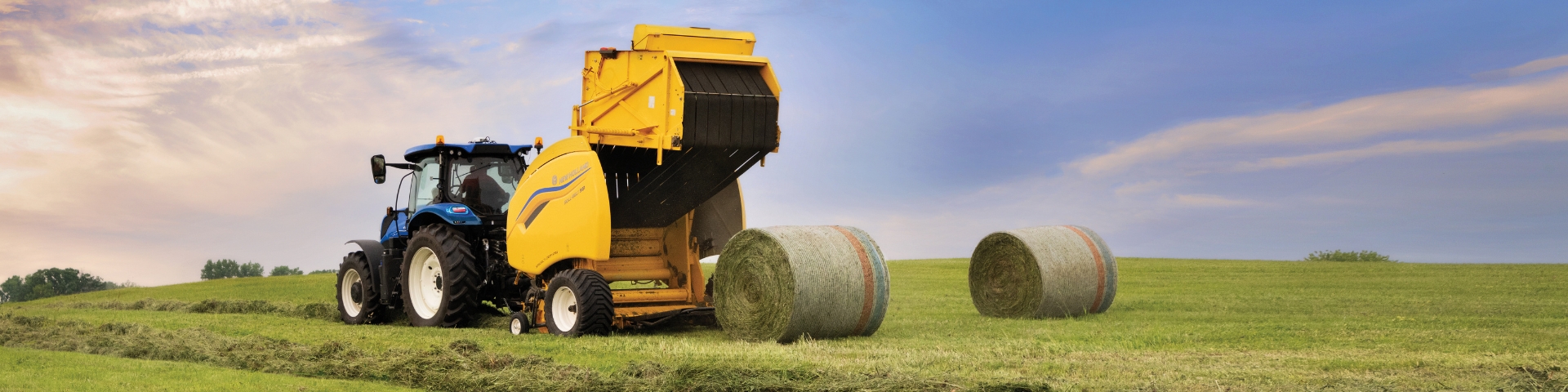 Yellow baler dropping round hay bales behind.