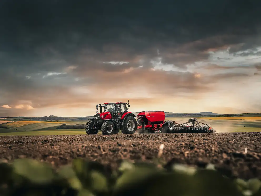 Case IH Puma 185 tractor with agricultural equipment working on a freshly tilled field at sunset