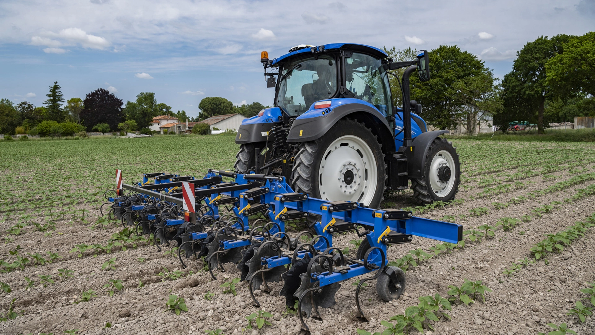 Tractor on a farm field, equipped with SRC & SRC SmartSteer Interrow Cultivators, tilling the soil between crop rows