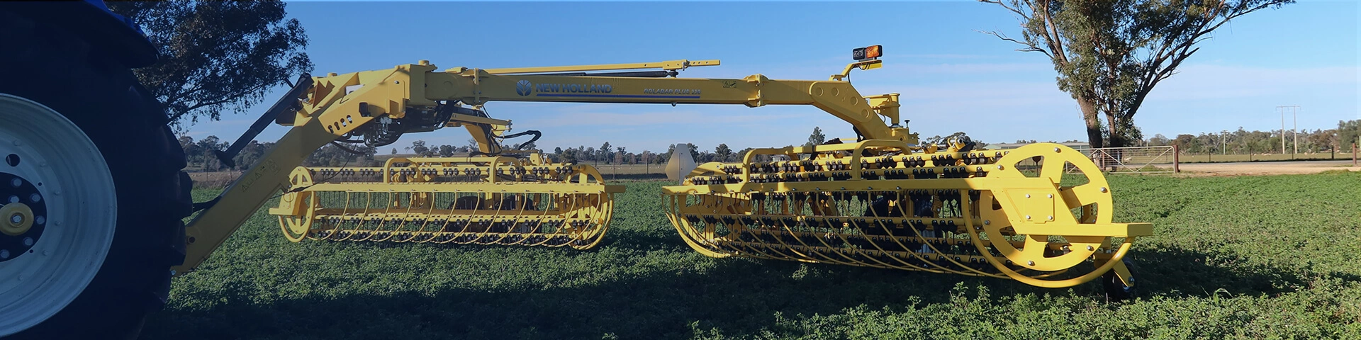 New Holland rolabar rake, roller bar working in field with New Holland tractor in Australia