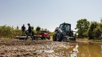 Two men working in muddy field.