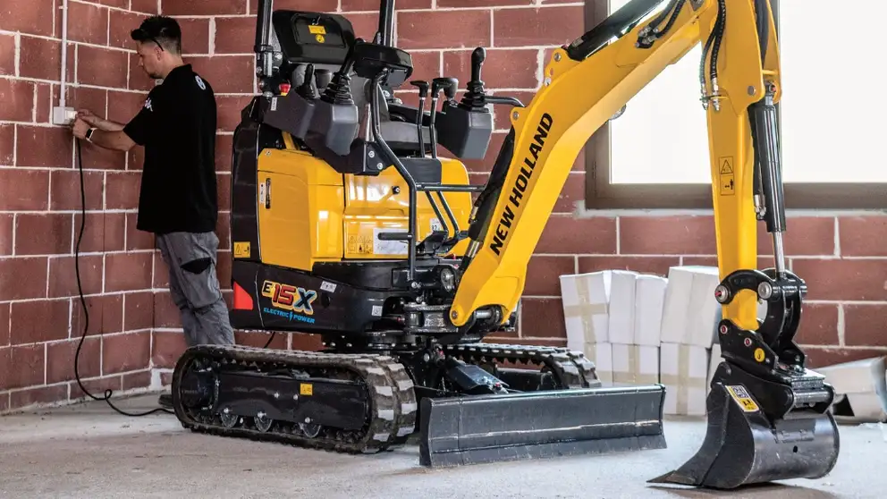 Operator plugs electric mini excavator in to charge