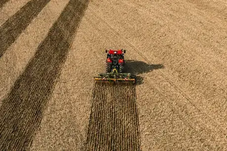 Red Case IH Puma next generation tractor sitting in field with implement attached